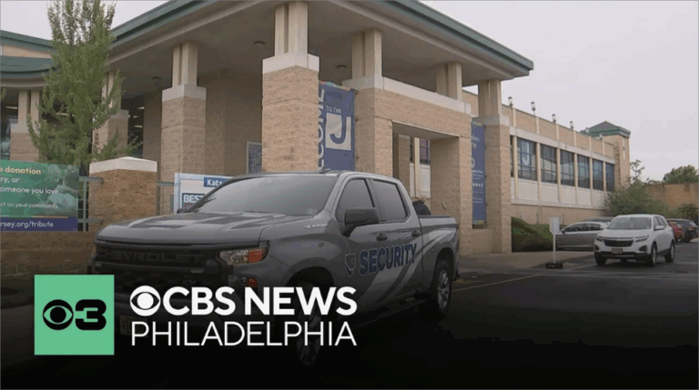 A gray Chevrolet pickup truck with "SECURITY" written on its side is parked in front of a building with stone pillars and a banner that says "WELCOME TO THE J". Other cars are visible in the parking lot, and a CBS News Philadelphia logo is in the bottom left corner.