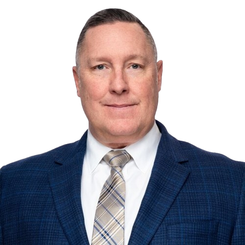A smiling middle-aged man with short brown hair, wearing a blue suit, white shirt, and a plaid tie.